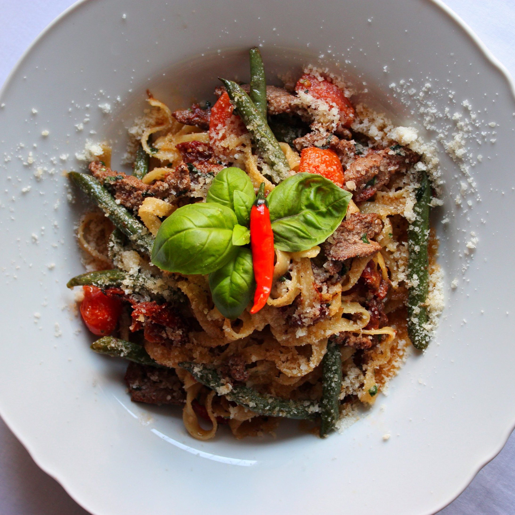 Tagliatelle-Nudeln mit Kalbfleisch, sonnengetrockneten Tomaten und Spargelbohnen